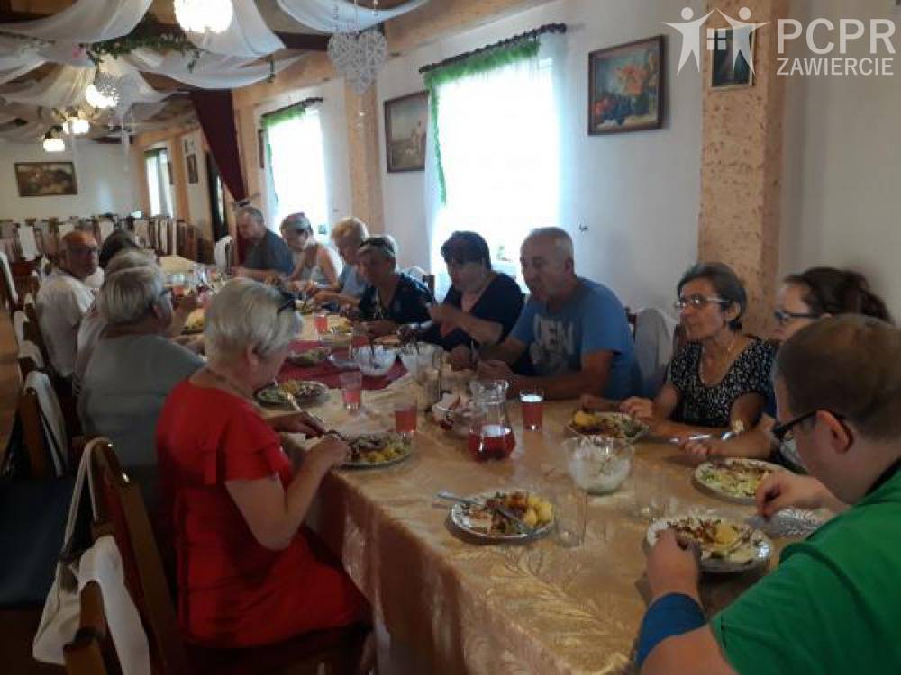 Zdjęcie: Grupa kobiet i mężczyzn je obiad przy stole